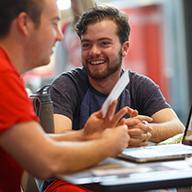 Two students smile while working together.